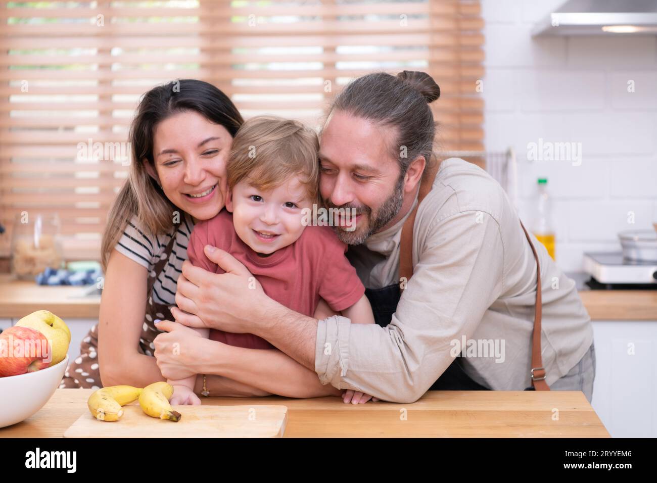 Mom and dad in the kitchen of the house with their small children. Have a good time making dinner together. Stock Photo