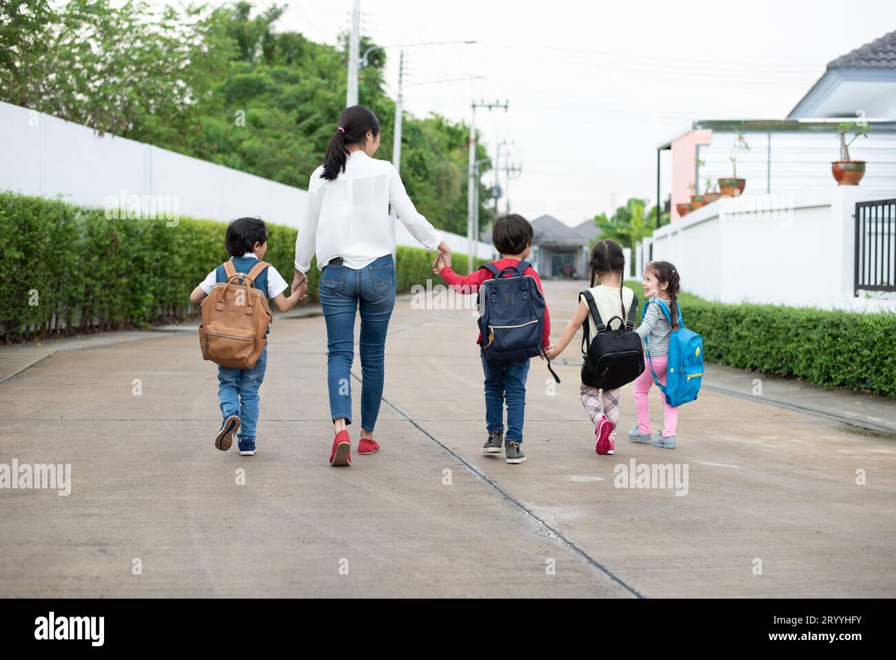 Group of preschool student and teacher holding hands and walking to home. Mom bring her children go to school together. Back to Stock Photo