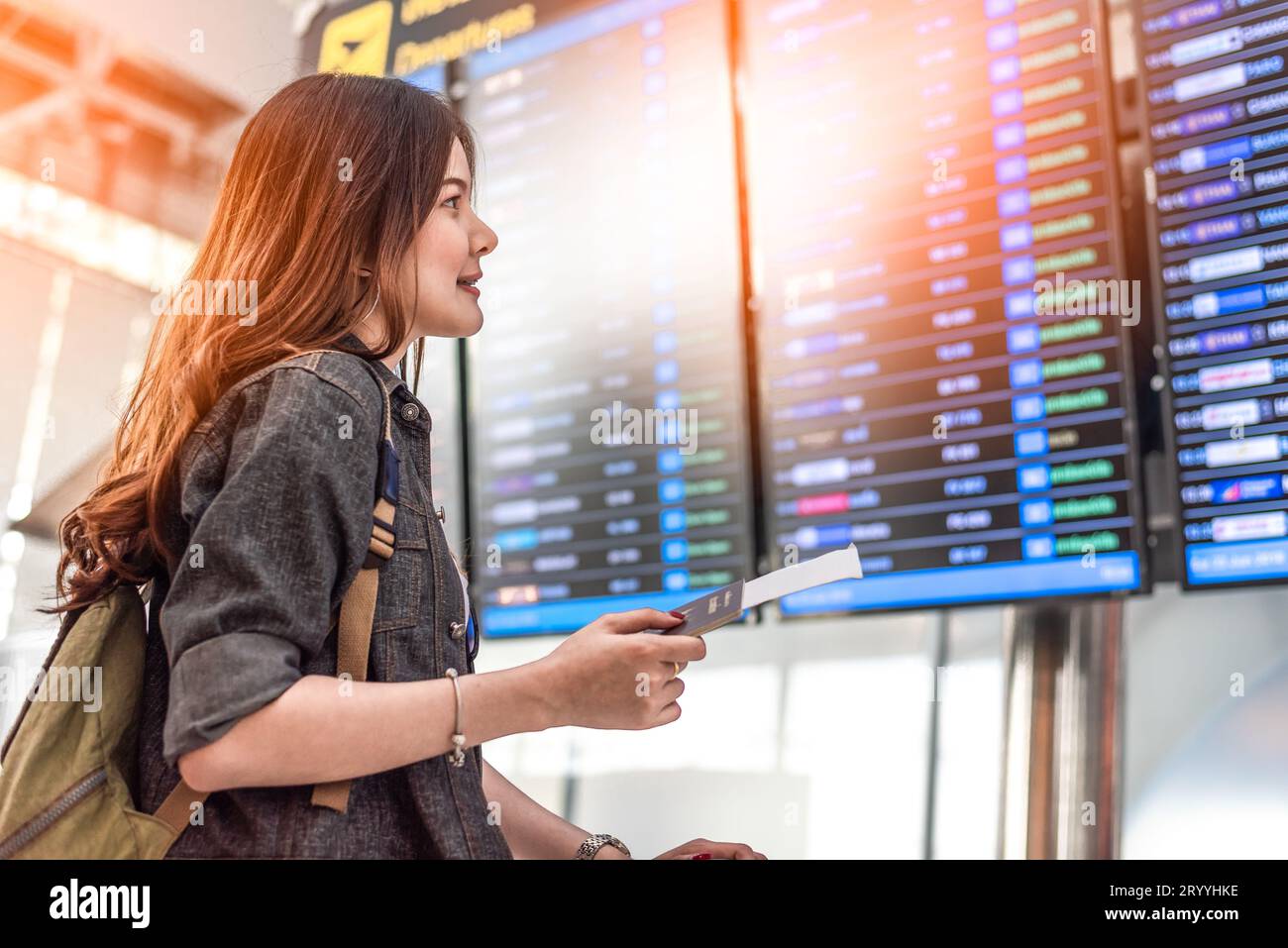 Beauty Asian female tourist looking at flight schedules for checking take off time. People and lifestyles concept. Travel and Ha Stock Photo