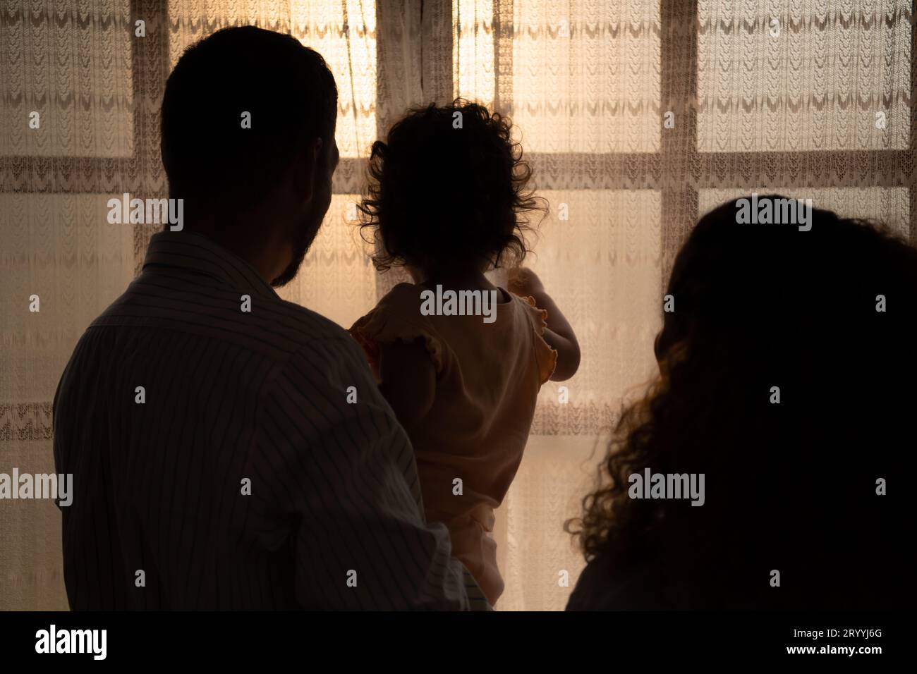 Parents and children enjoy the morning sunlight shining through the bedroom window in the house. Stock Photo