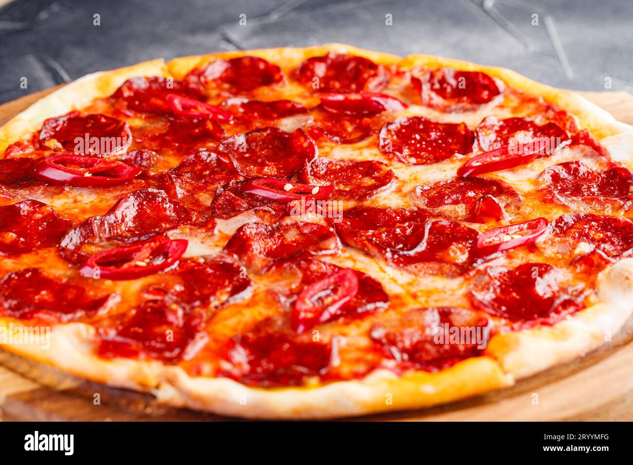 Pepperoni pizza on wooden board on dark background. Close-up Stock Photo