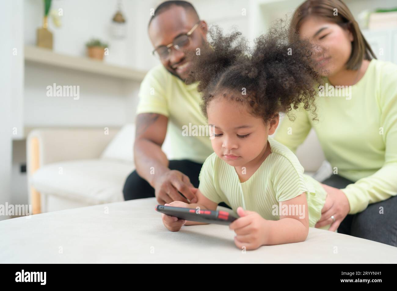Little children play and learn things in the wide world on tablet. with parents to supervise and help in the living room of the Stock Photo