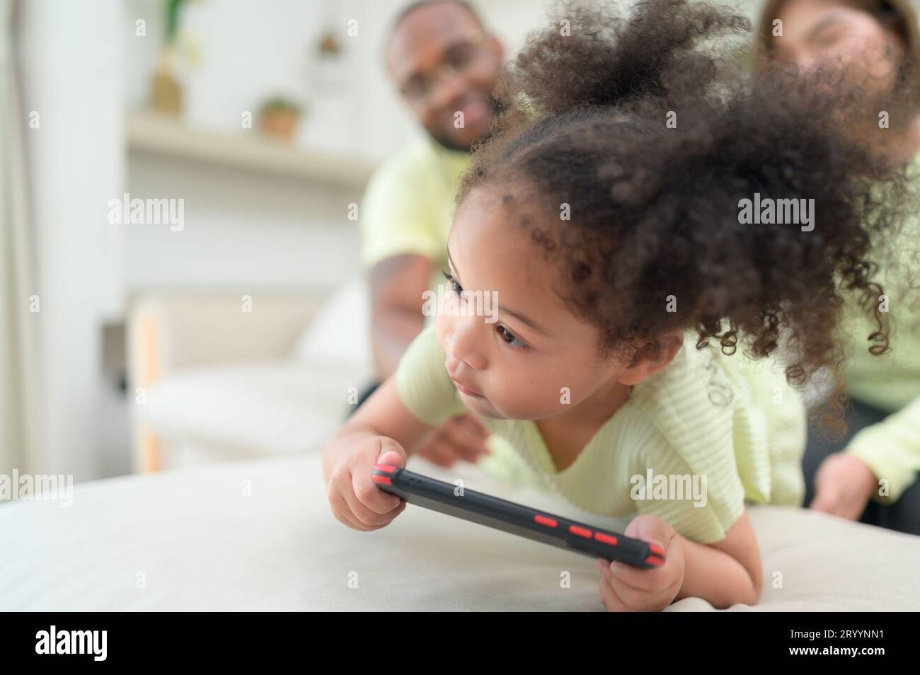 Little children play and learn things in the wide world on tablet. with parents to supervise and help in the living room of the Stock Photo