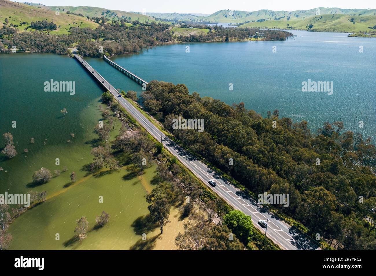 An aerial view of a large bridge running over Lake Eildon, flanked by green water mixed with muddy water whipped up by currents, in Victoria, Australi Stock Photo