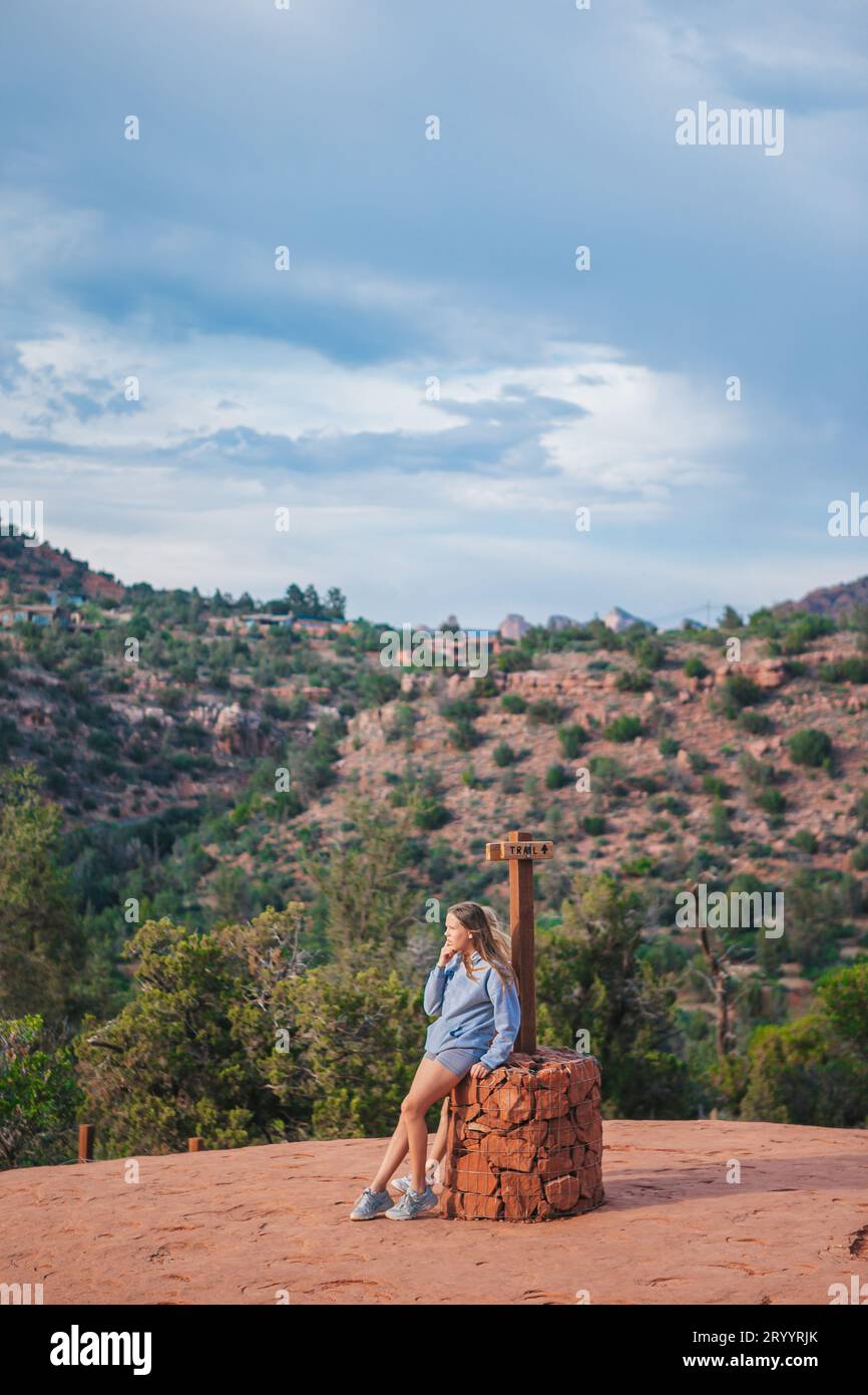 Little girl on the edge of a cliff at Cathedral Rock in Sedona, Arizona. View from Scenic Cathedral Rock in Sedona with blue sky Stock Photo