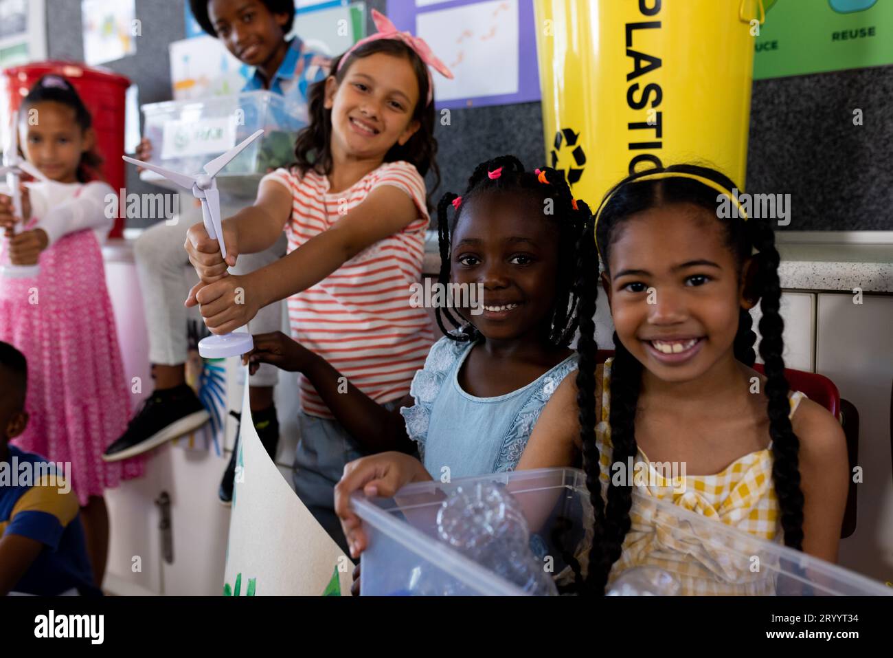 Portrait of happy diverse children with ecology items and plants in class at elementary school Stock Photo