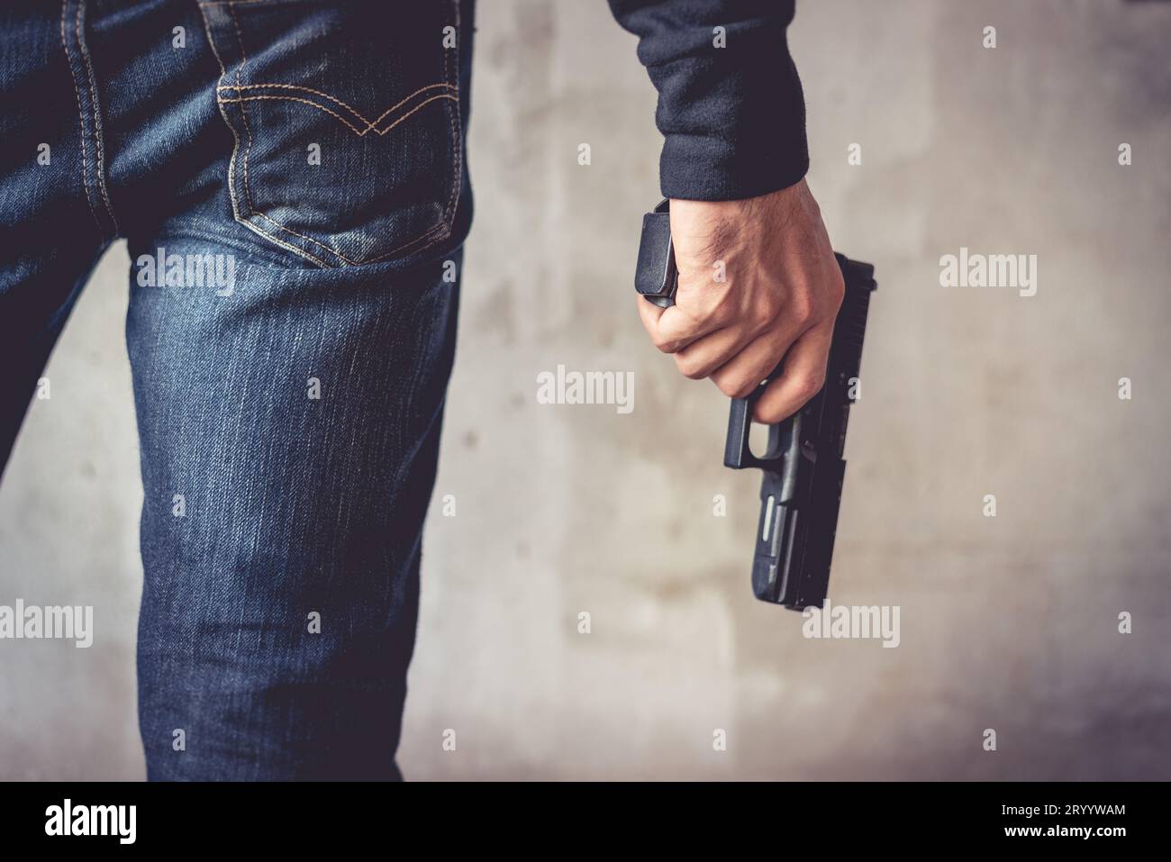Close up of man holding hand gun. Man wearing blue jeans. Terrorist and Robber concept. Police and Soldier concept. Weapon theme Stock Photo