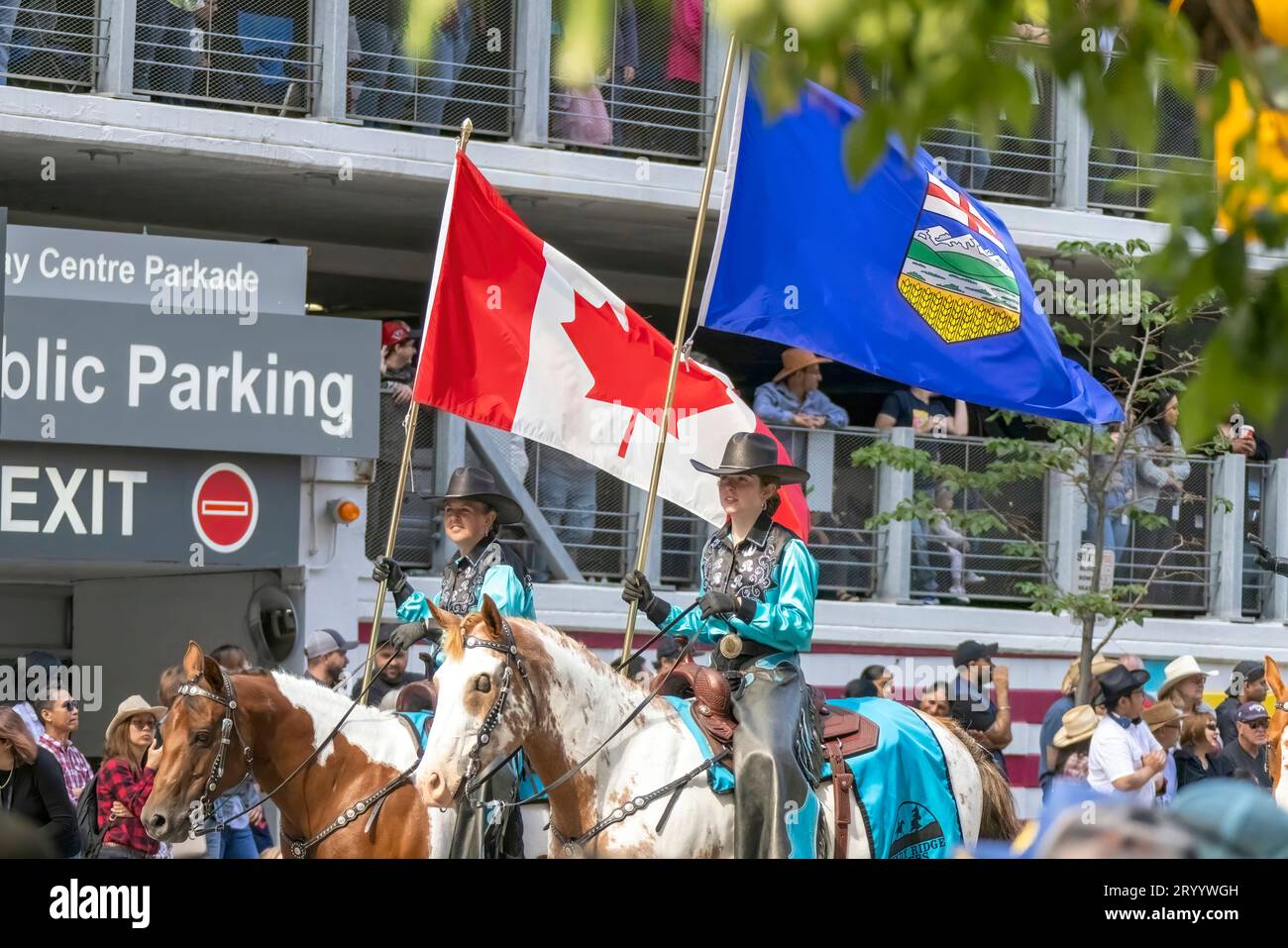 Calgary, Alberta, Canada. July 7, 2023.A couple of people riding horses holding a Canadian flag an Alberta flagat a public parad Stock Photo