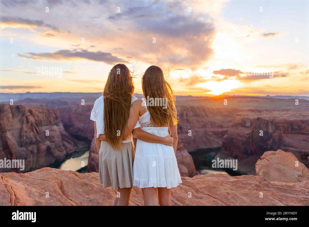 Happy girls on the edge of the cliff at Horseshoe Band Canyon in Paje, Arizona. Adventure and tourism concept. Beautiful nature Stock Photo