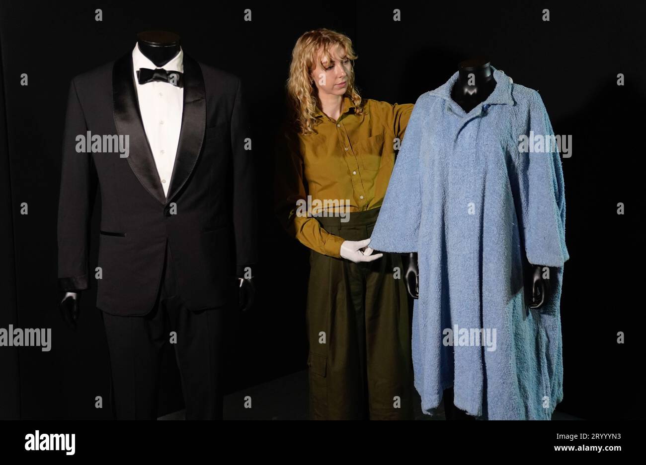 A Propstore employee adjusts Honey Ryder's (Ursula Andress) bathrobe from the 1962 James Bond film 'Dr No' (estimate £70,000 - 140,000) which is alongside Daniel Craig's tuxedo from the 2021 James Bond film 'No Time To Die' (estimate £20,000 - 40,000) during a preview for the showbiz memorabilia auction, at the Propstore in Rickmansworth, Hertfordshire. Picture date: Wednesday September 20, 2023. Stock Photo
