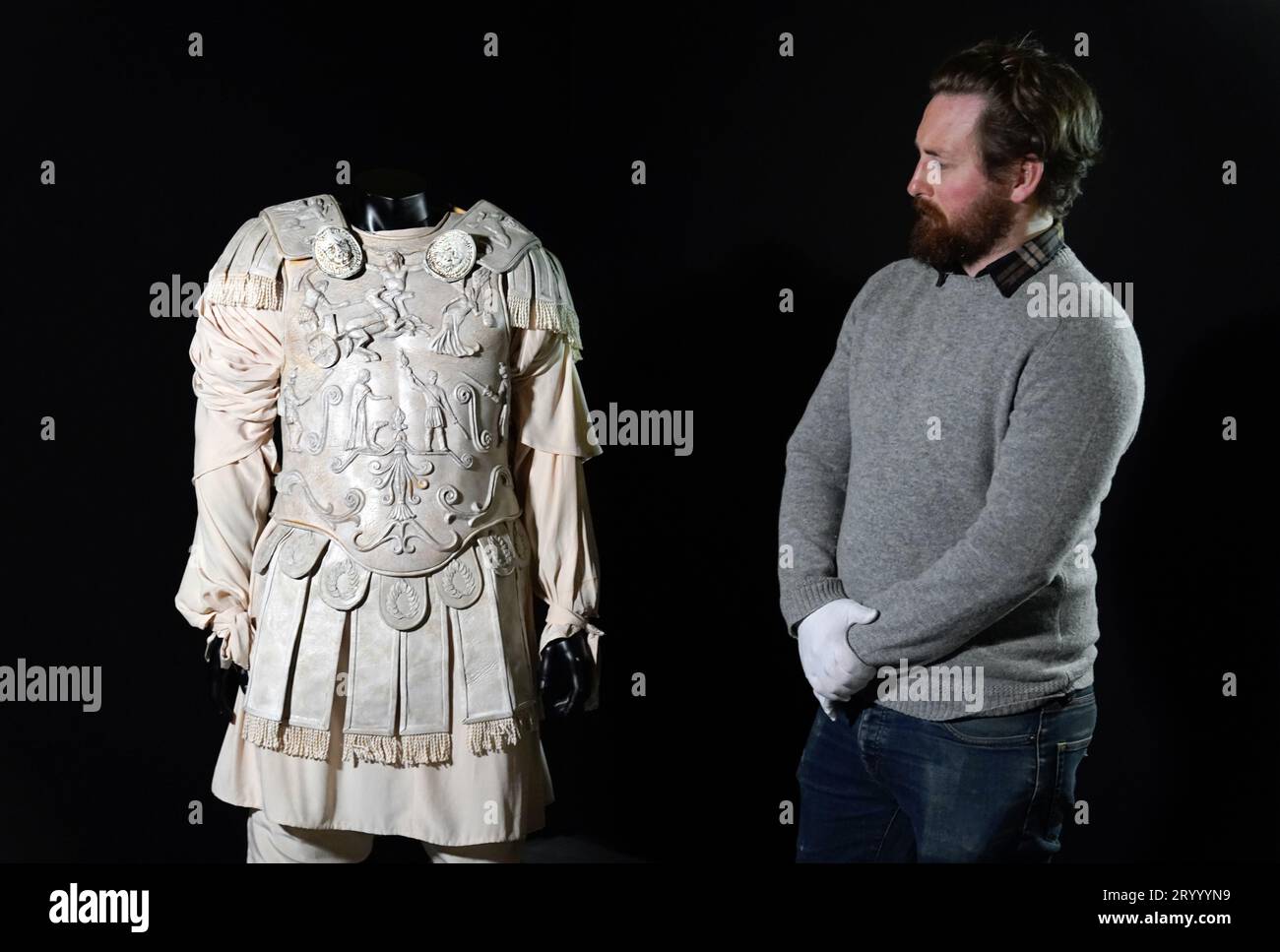 A Propstore employee looks at a Commodus (Joaquin Phoenix) screen matched arena costume from the 2000 film 'Gladiator' (estimate £30,000 - 60,000) during a preview for the showbiz memorabilia auction, at the Propstore in Rickmansworth, Hertfordshire. Picture date: Wednesday September 20, 2023. Stock Photo