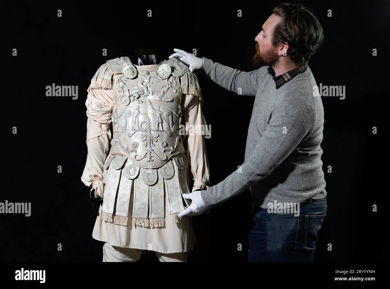 A Propstore employee adjusts a Commodus (Joaquin Phoenix) screen matched arena costume from the 2000 film 'Gladiator' (estimate £30,000 - 60,000) during a preview for the showbiz memorabilia auction, at the Propstore in Rickmansworth, Hertfordshire. Picture date: Wednesday September 20, 2023. Stock Photo