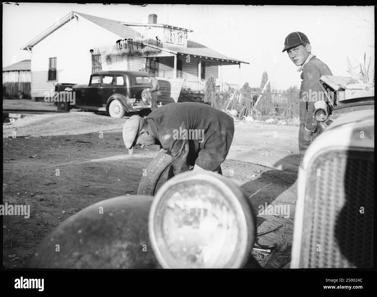 Athens, Tennessee, USA. 1938.  Car cemetery; Two men, one holding a rubber tire, next to a car. Archive Photograph in 1930s by Annemarie Schwarzenbach of depression America Stock Photo