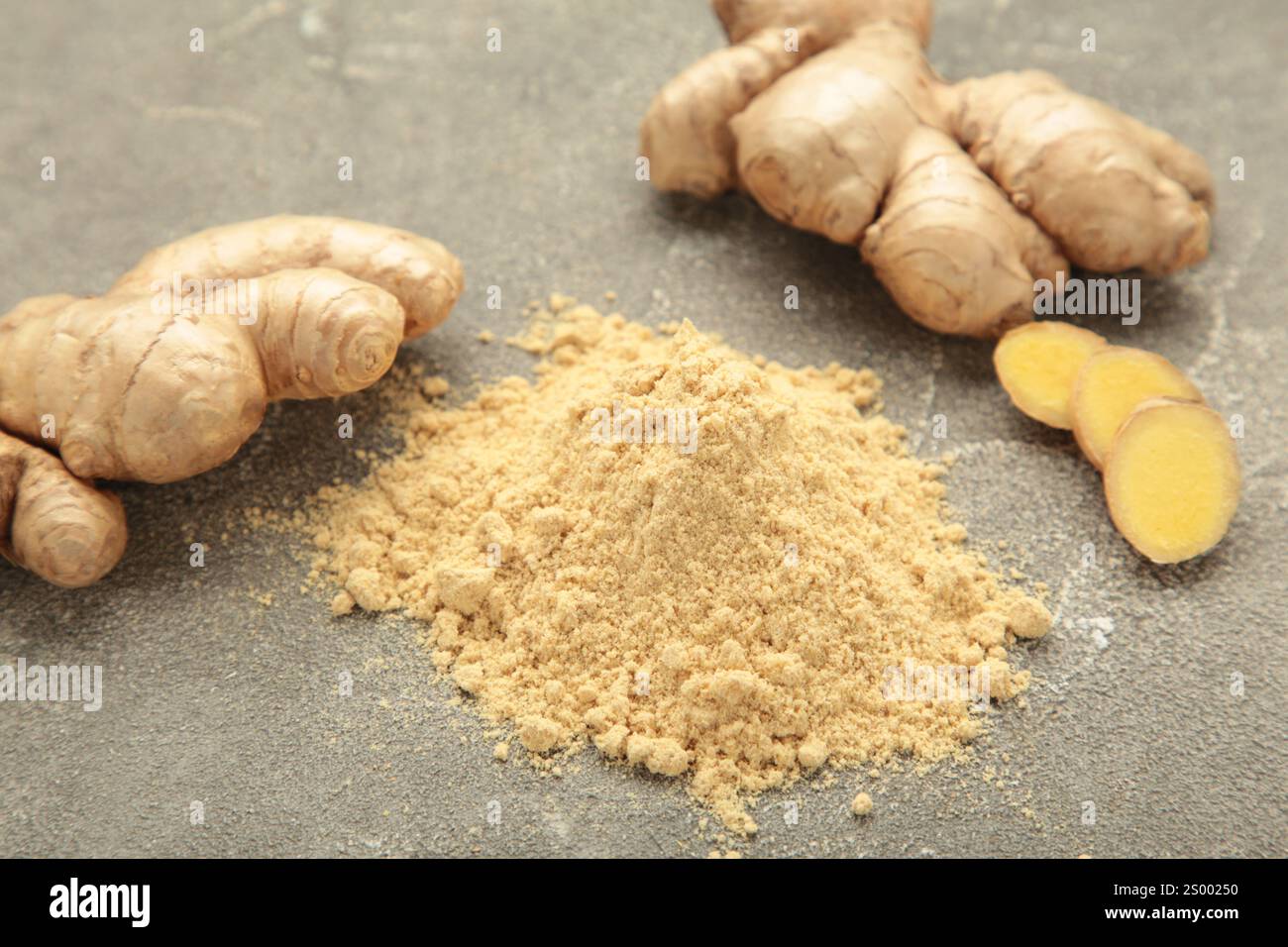 Ginger powder with fresh ginger root on grey concrete background. Stock Photo