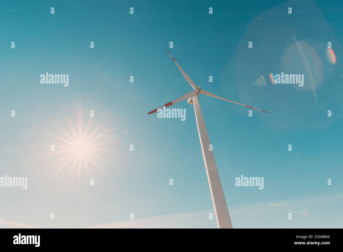 Wind turbine generating clean energy under blue sky with bright sun and ...