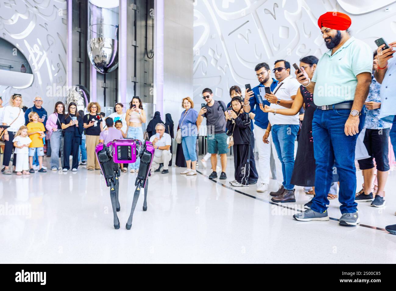 Dubai, UAE - December 9, 2024: Modern futuristic Museum of Future. Snow-white interior inside museum with Arabic script on walls. Robot dog plays with visitors Stock Photo
