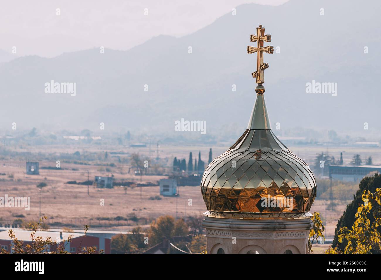 Golden dome of a church with a cross on top, overlooking a rural ...