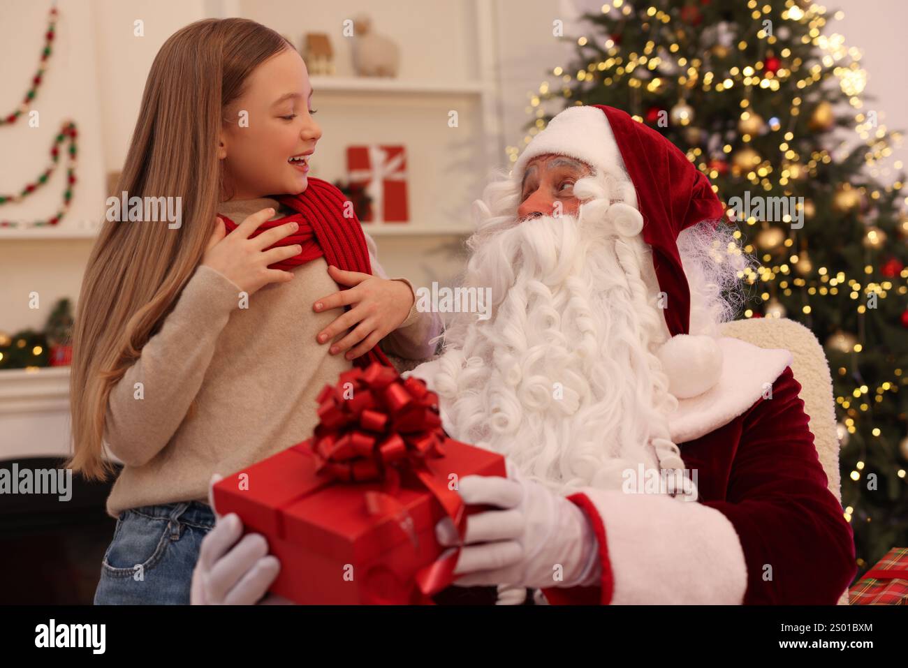 Christmas celebration. Santa Claus giving gift box to girl at home ...