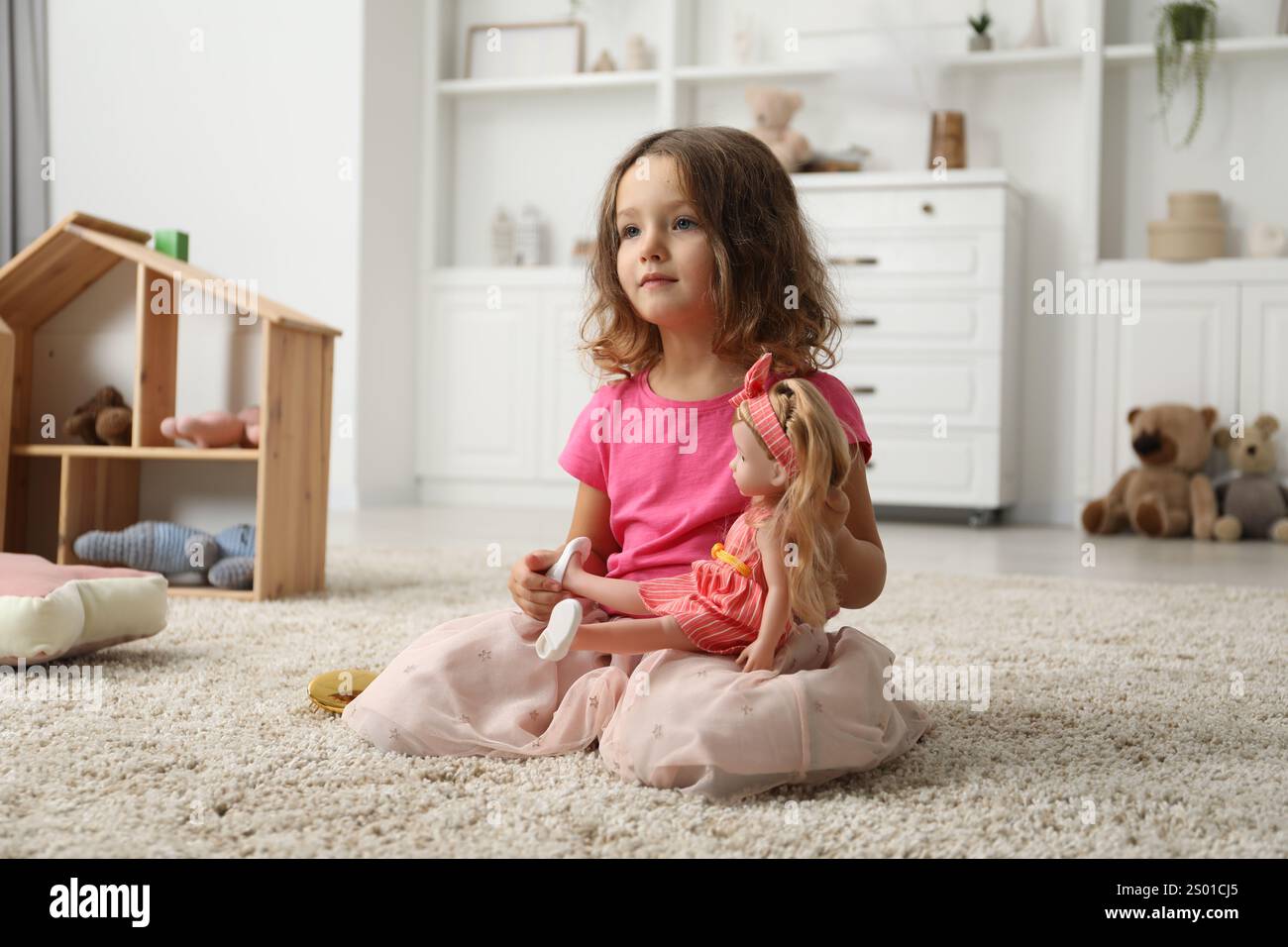 Cute little girl playing with her doll on floor at home Stock Photo - Alamy