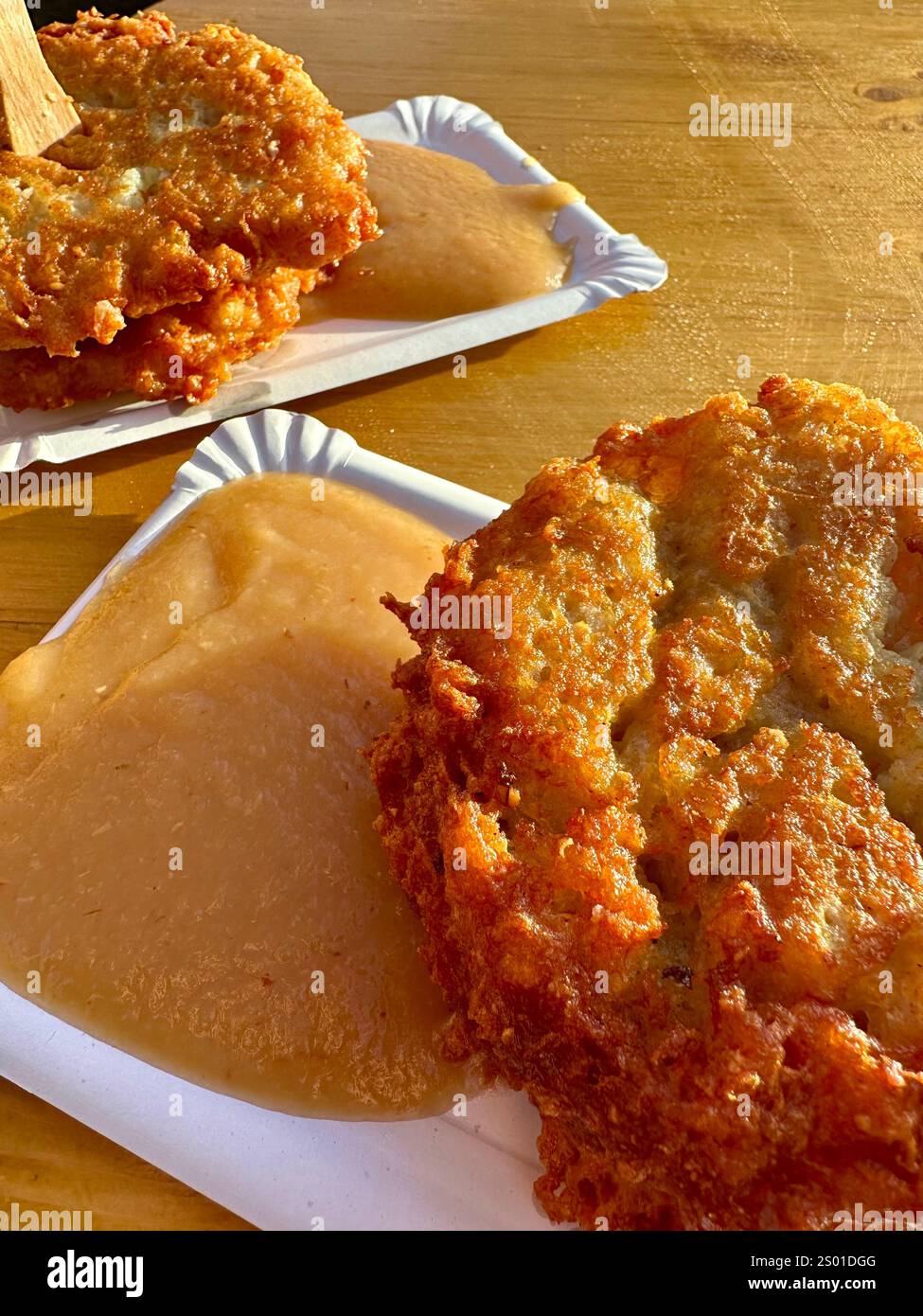 Two Potato pancakes with apple sauce on paper plates on a wooden table - Smartphone Captured Stock Image