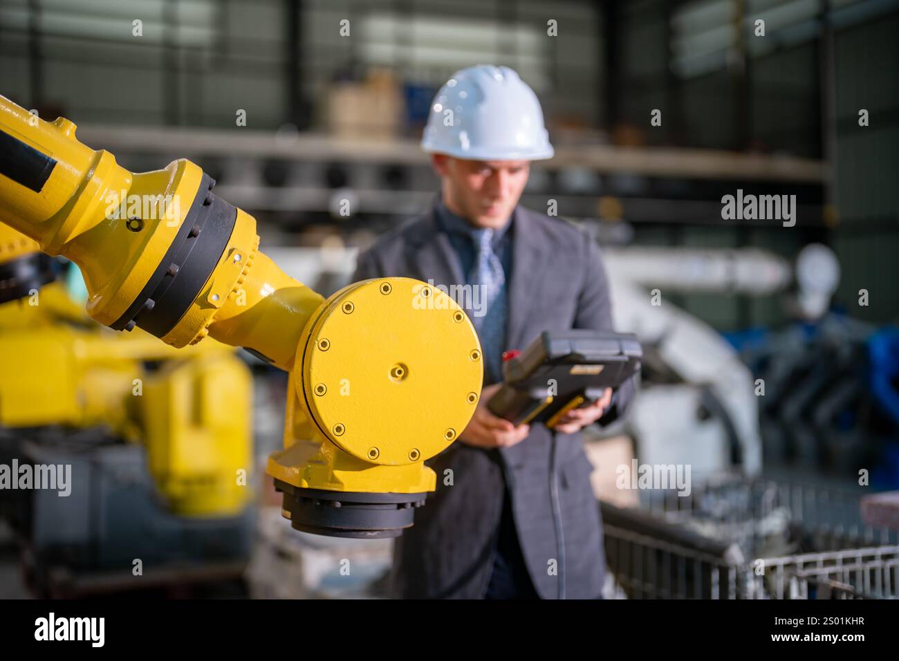 Robotics Operator A man in professional attire operates a robotic arm in a manufacturing ...
