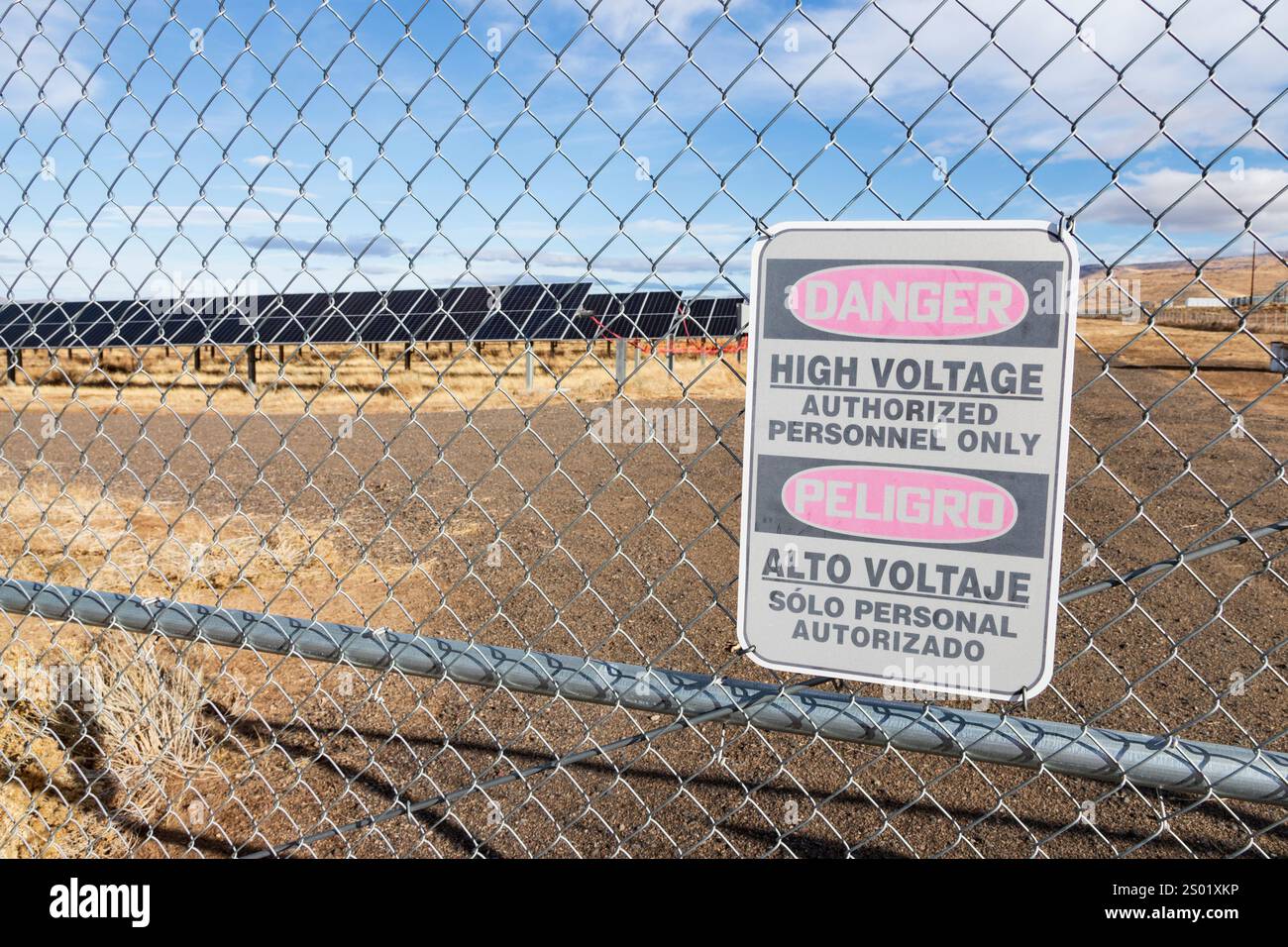 Signage outside a large solar farm in the northwestern nevada desert warns of high voltage danger in English and Spanish Stock Photo