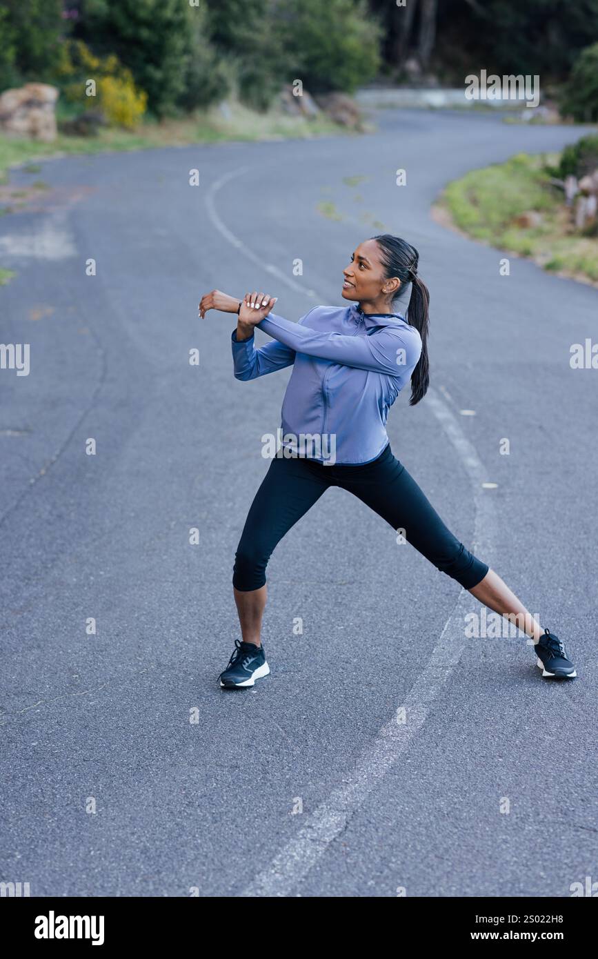 Young slim female warming up her body on an abandoned empty road Stock Photo