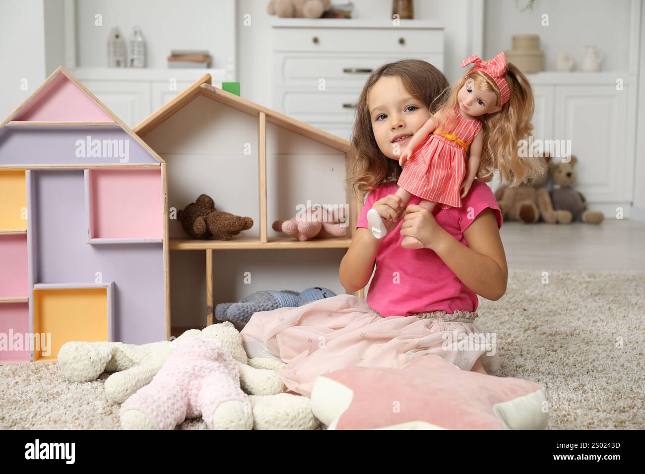 Cute little girl playing with her doll at home Stock Photo - Alamy