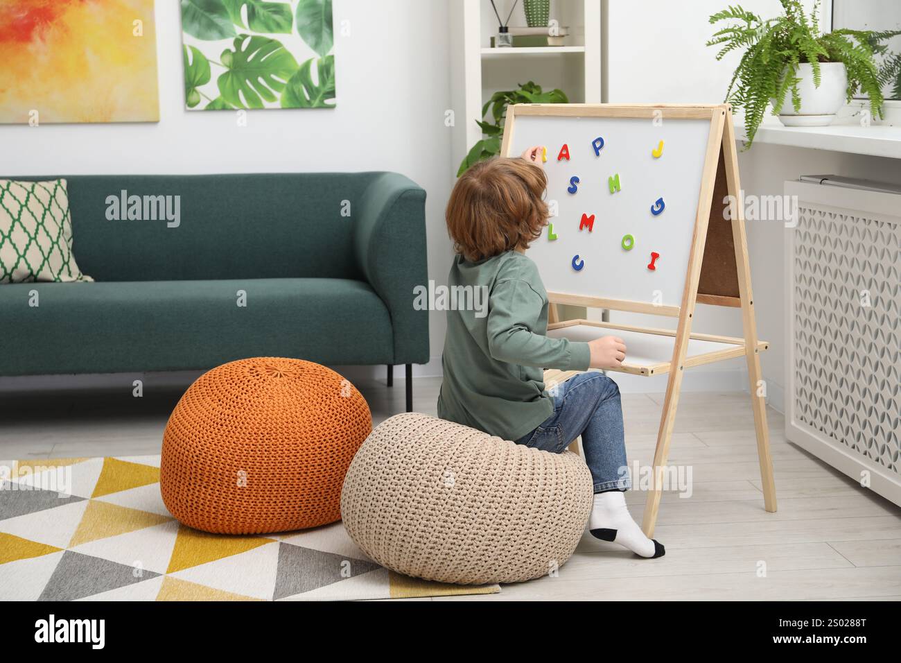 Little boy assembling letters on magnetic board indoors Stock Photo - Alamy