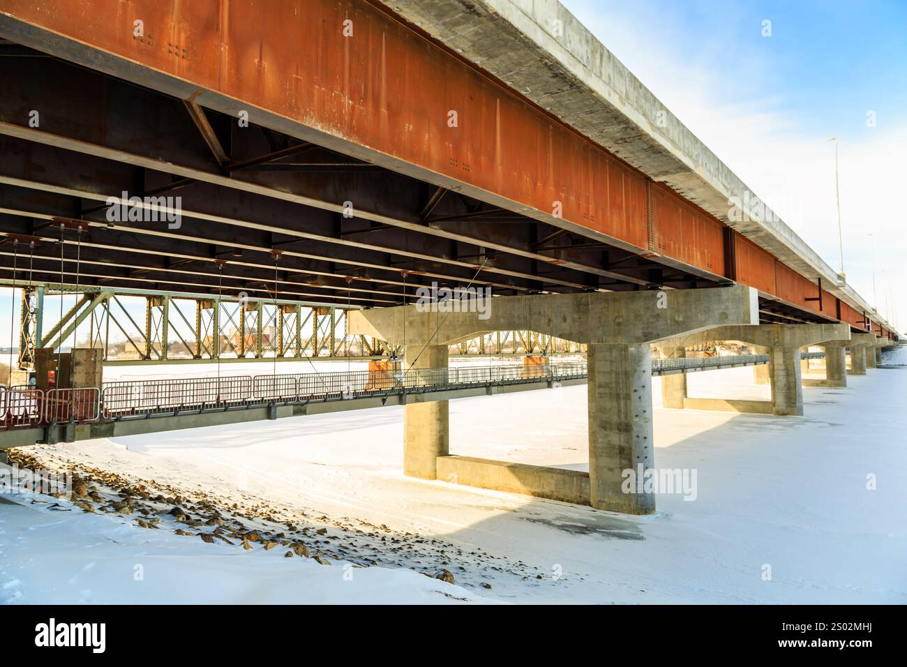 A bridge with a lot of metal and concrete. The bridge is very long and has a lot of pillars Stock Photo