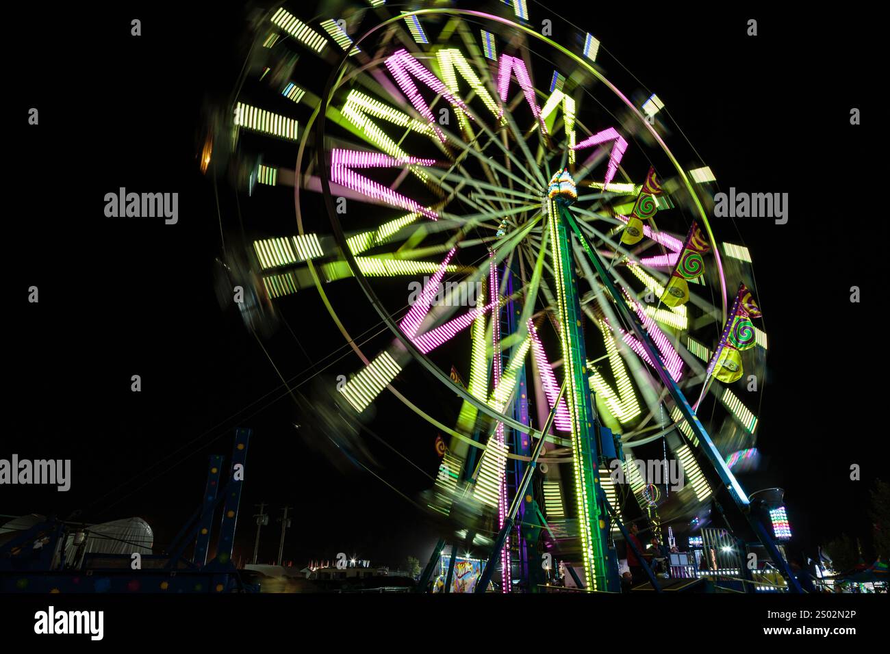 A carnival ride with bright lights and people on it is spinning in the ...