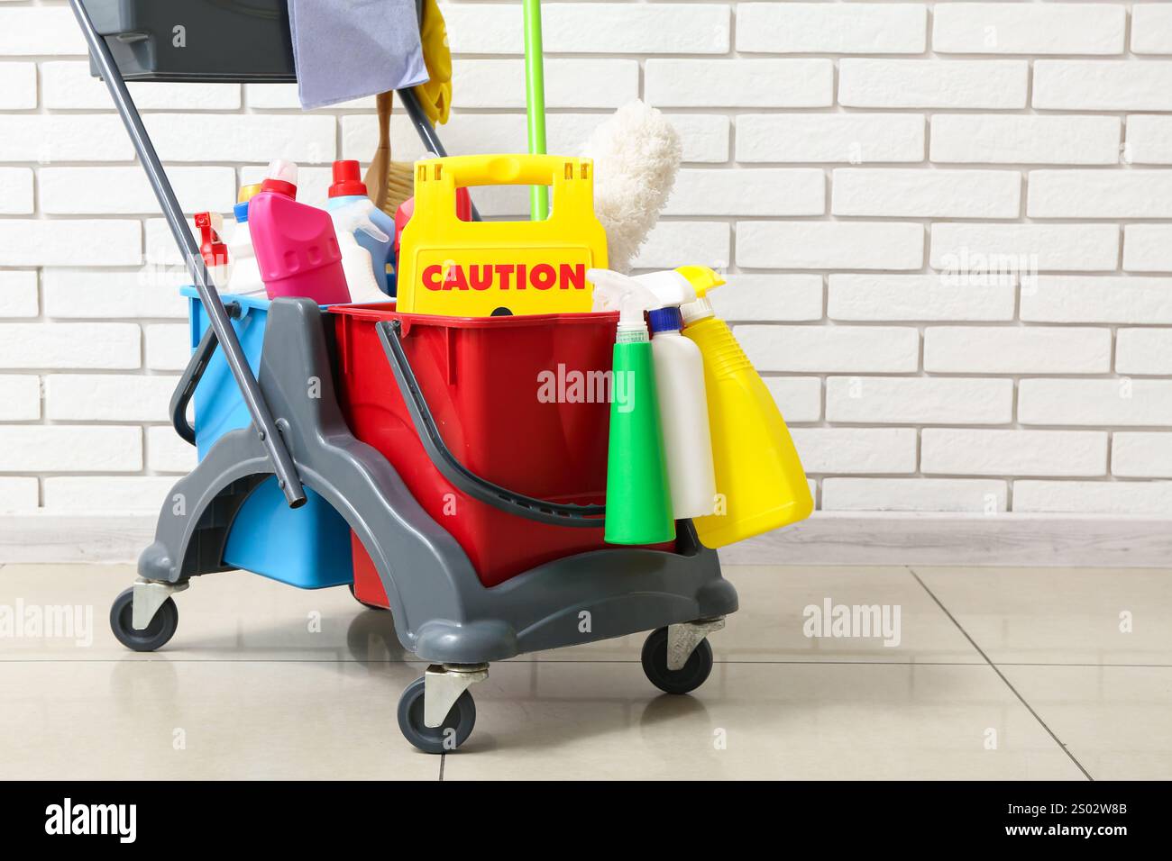 Caution sign with janitor's trolley near white brick wall Stock Photo ...