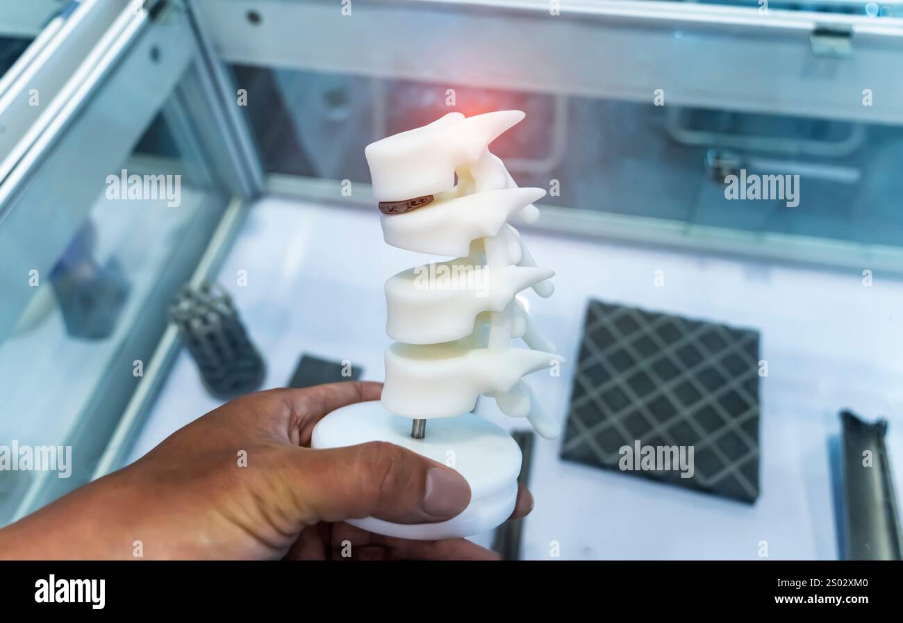 hand with 3d printed human spine in 3d printer. Stock Photo