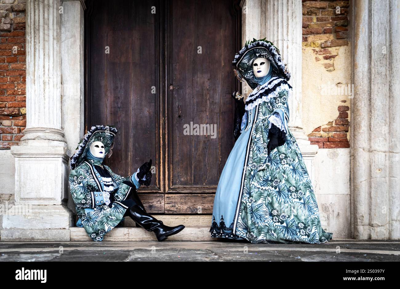 Two elegantly dressed individuals in elaborate costumes and masks ...