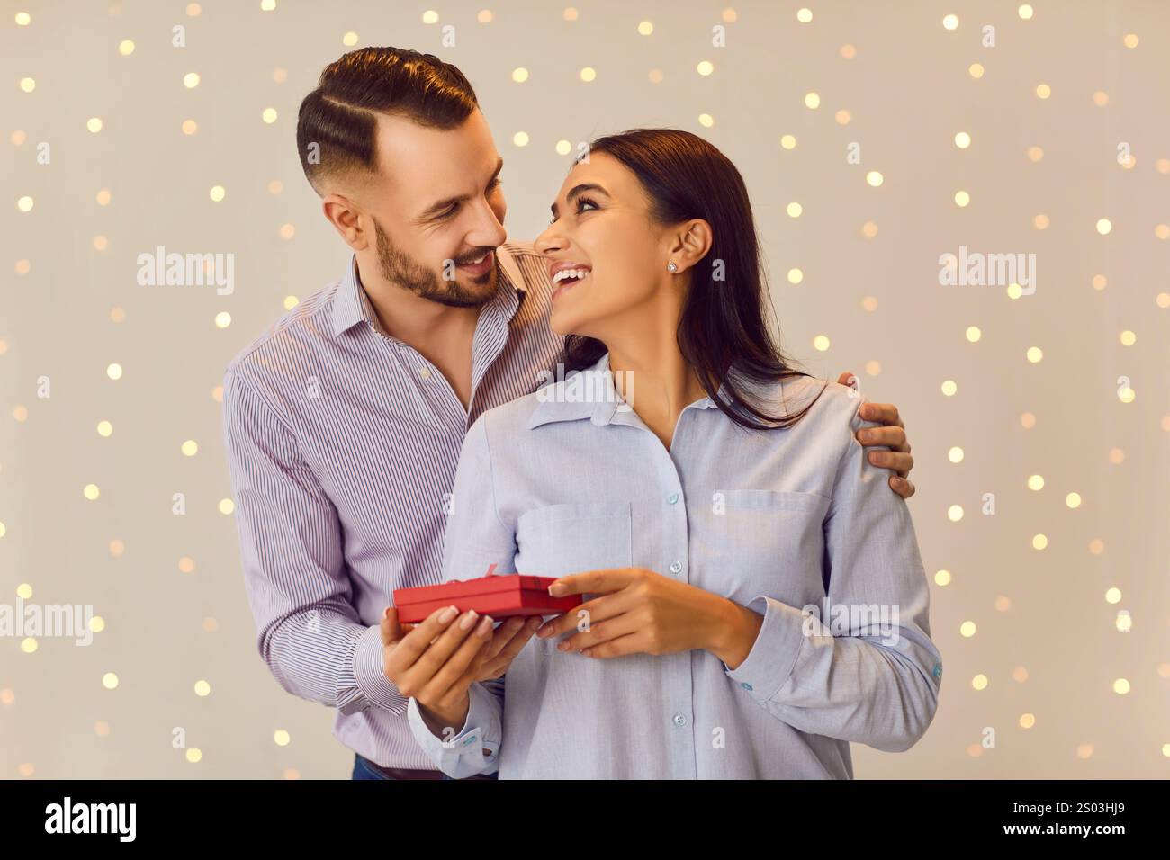 Valentine Day. Happy smiling couple in love standing together with red present gift box and hugging. Stock Photo