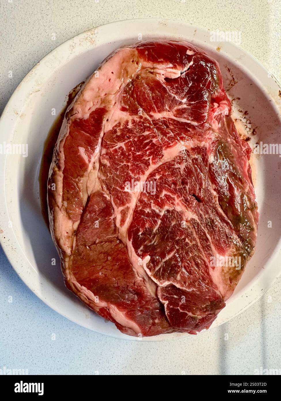 Large raw, marbled beef chuck roast ready for seasoning before being transferred to a roasting pan. - Smartphone Captured Stock Image