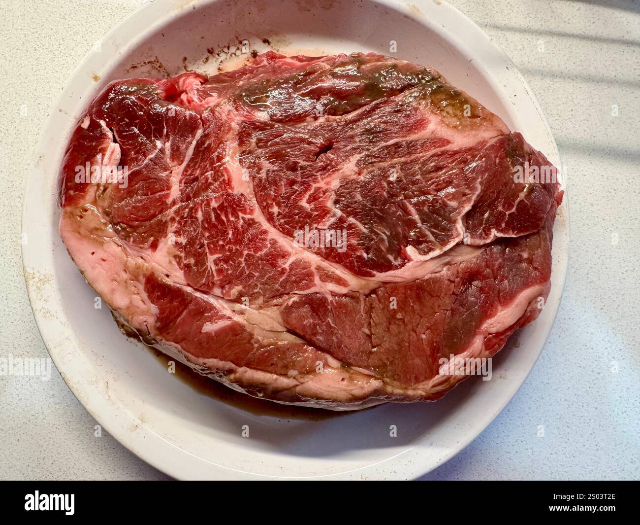 Large raw, marbled beef chuck roast ready for seasoning before being transferred to a roasting pan. - Smartphone Captured Stock Image