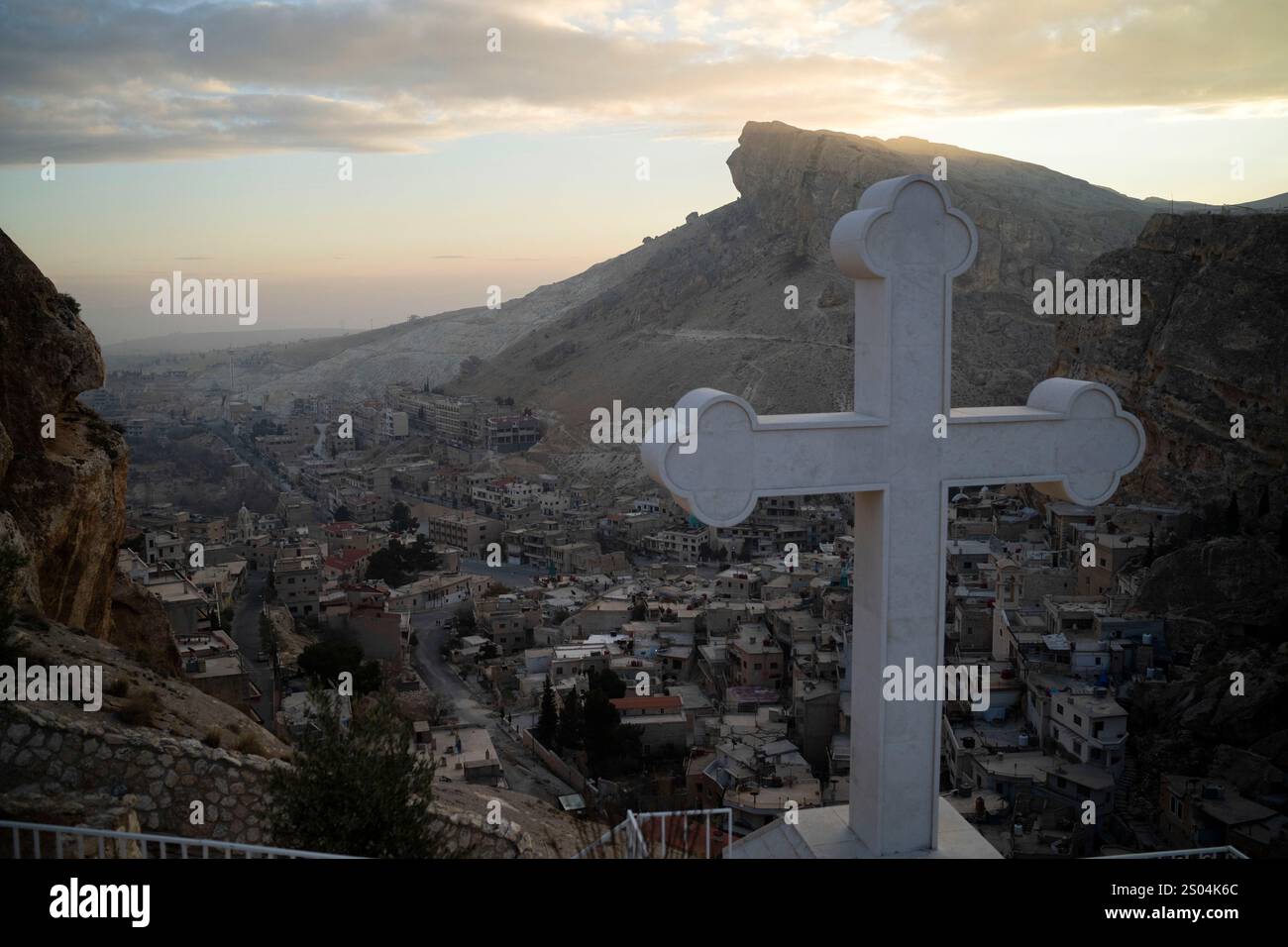 Houses are seen along the mountain as a cross stands over the Greek
