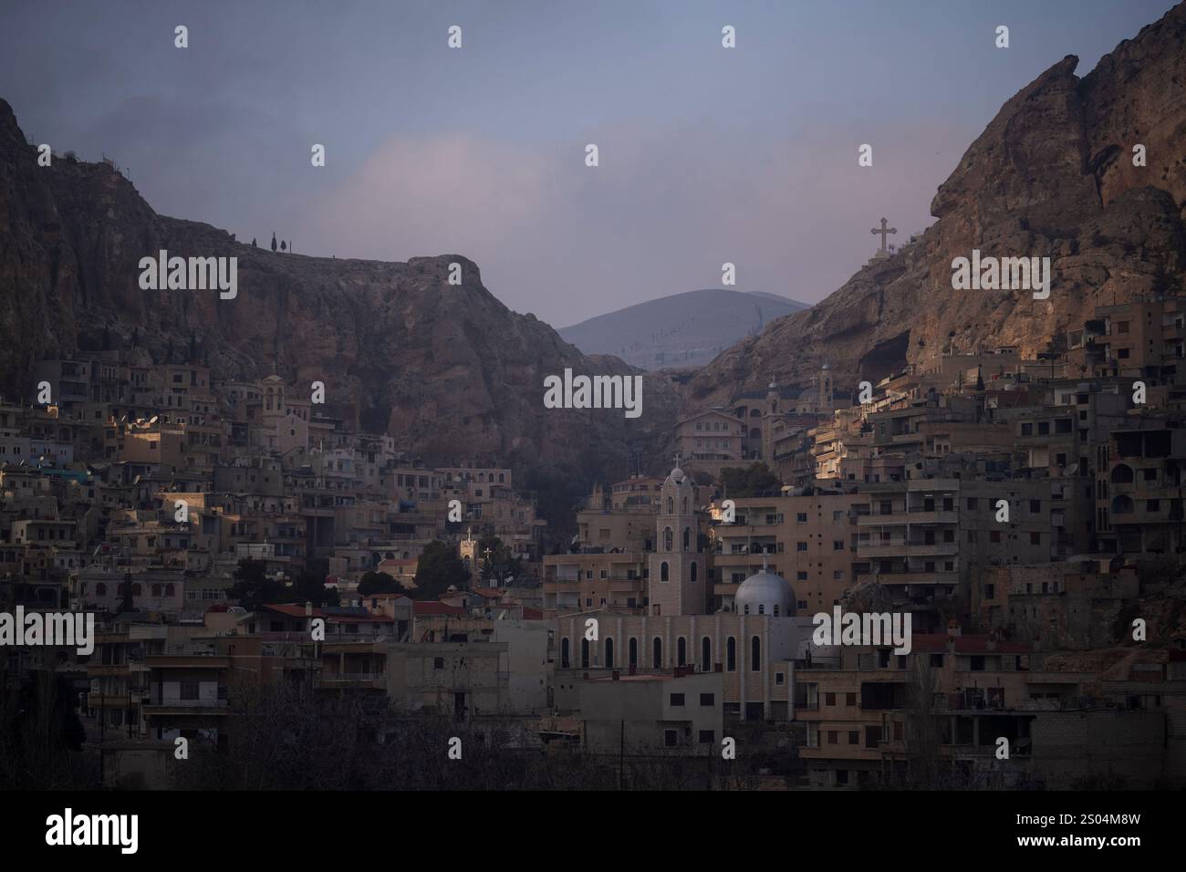 Houses are seen along the mountain as a cross stands over the Greek