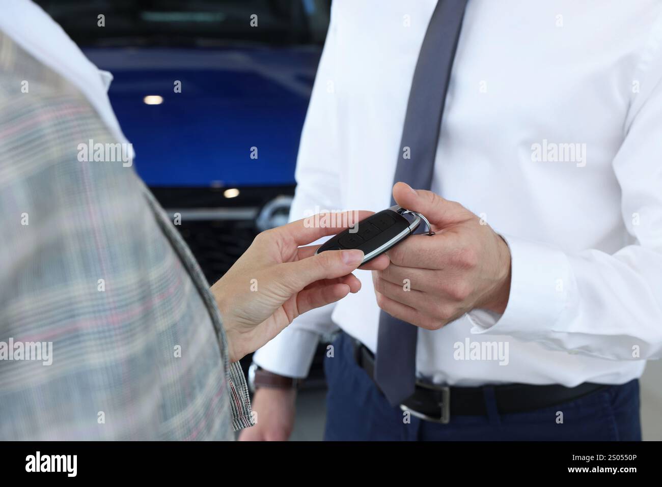 Saleswoman giving key to client near new car in salon, closeup Stock ...