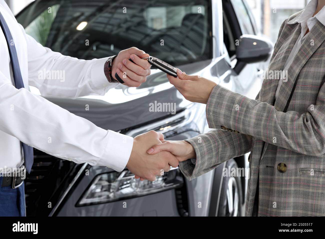 Salesman giving key to client near new car in salon, closeup Stock ...