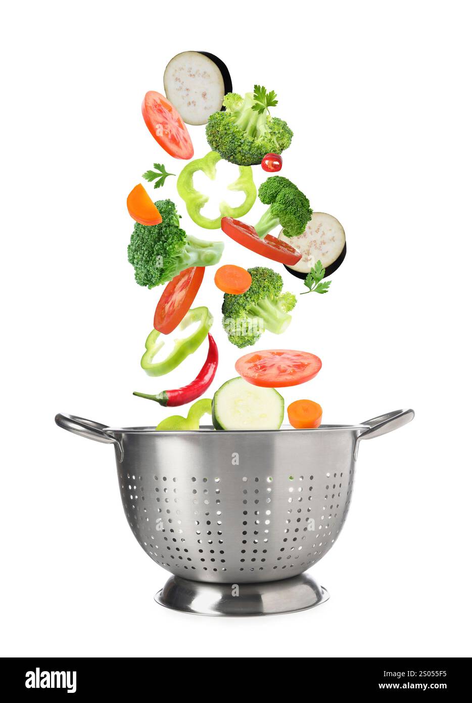 Different fresh vegetables falling into colander on white background Stock Photo