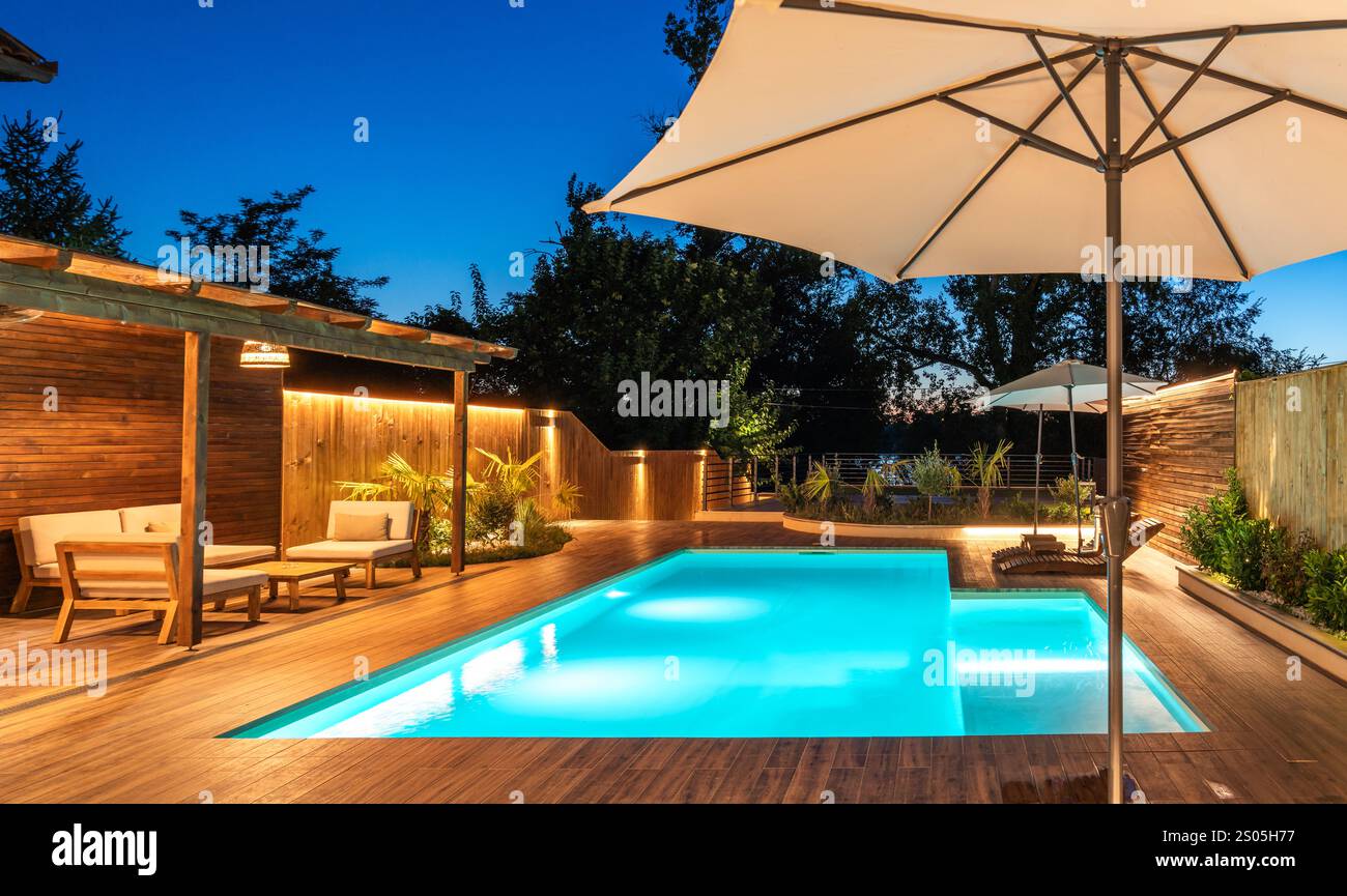 Backyard swimming pool with wooden deck and large umbrella in cozy ...