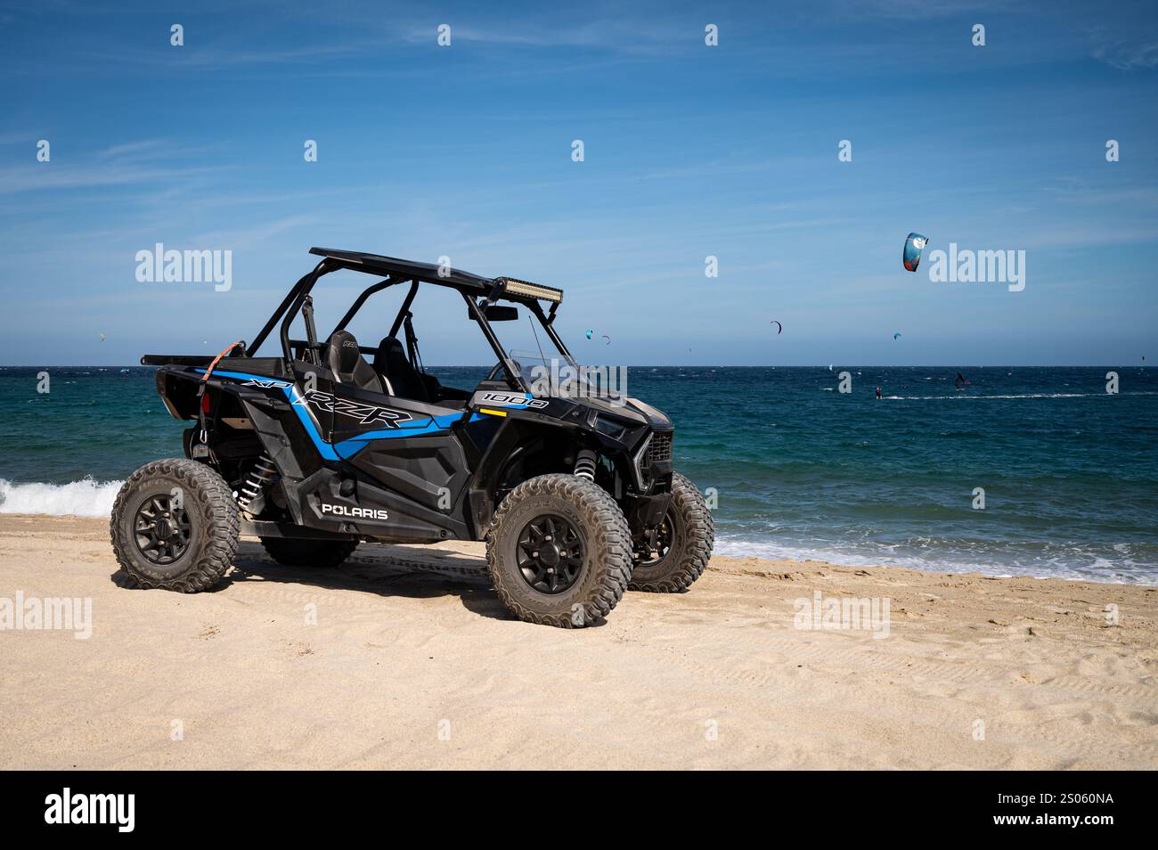 A Polaris RZR XP all-terain vehicle, parked on the Los Barriles beach with kite surfers in the background. They are a popular means of transport. Stock Photo