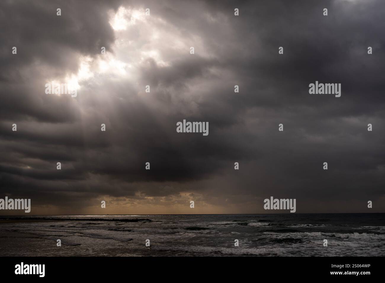 Calm Mediterranean sea with sun rays falling through dark clouds seen ...
