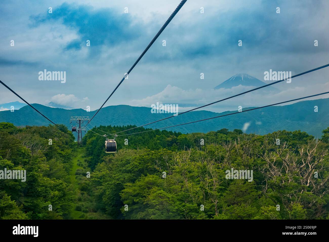 The bird's eye view of a cloud covered Mt. Fugi, along the Mt. Komagatake Ropeway in Japan during an overcast, summer day. The attraction is a popular Stock Photo