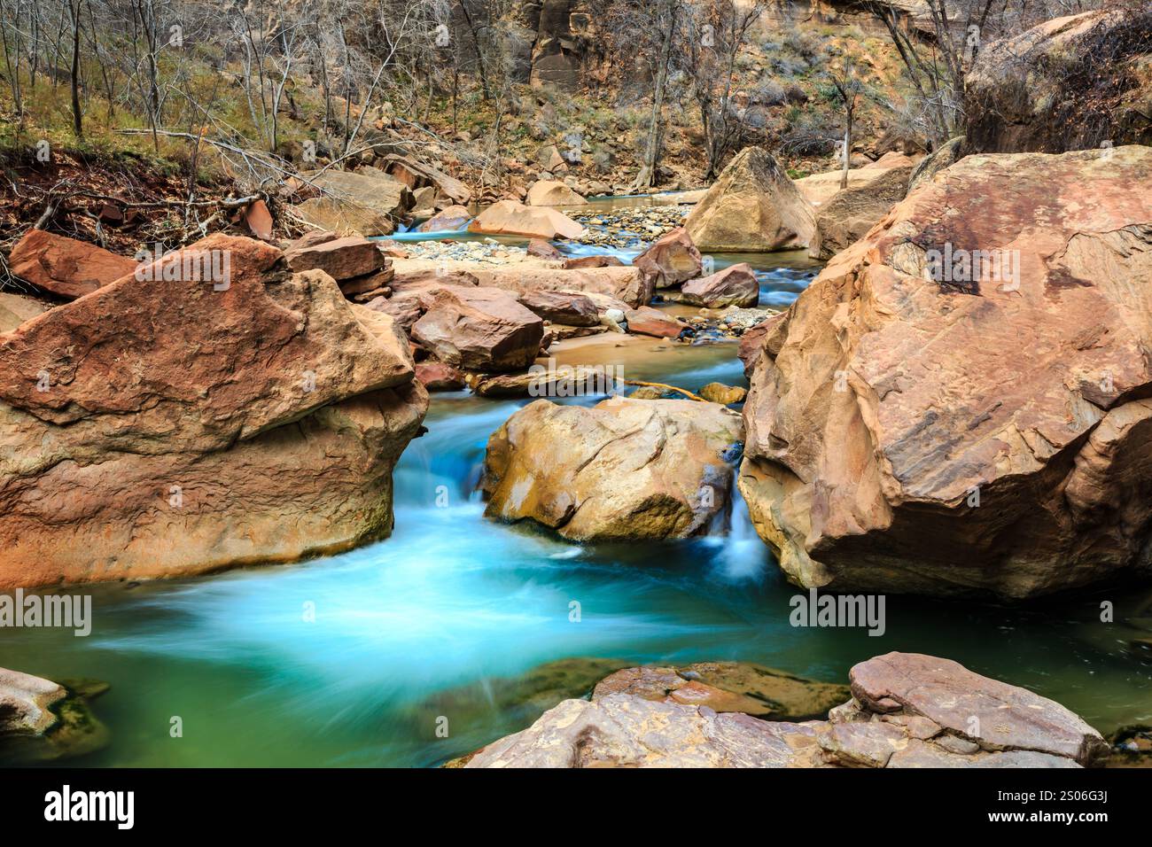 Flow Between Rocks A stream of water flows between large rocks. The water is a bright blue ...
