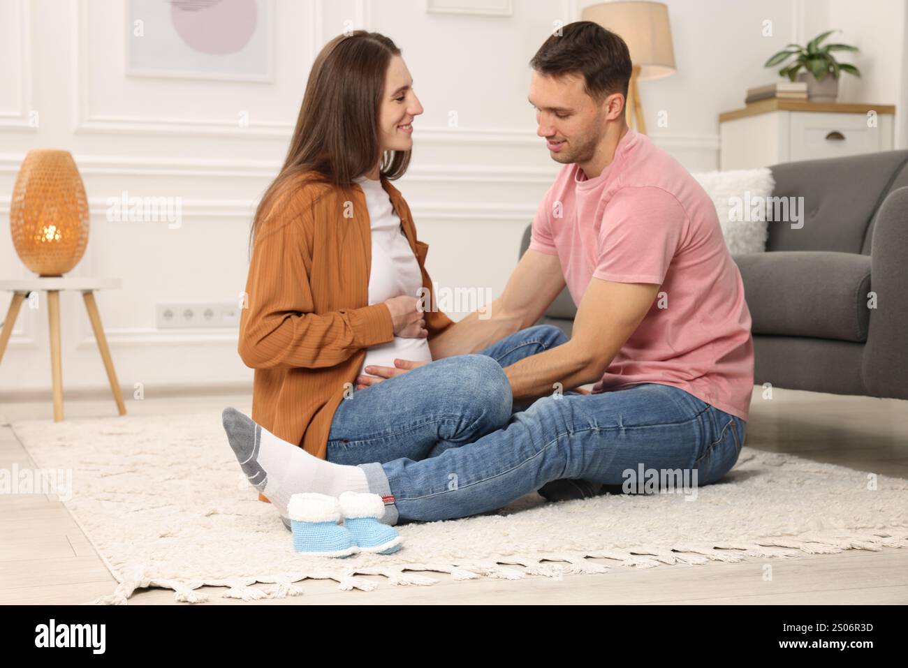 Man trying to feel baby kicks in his pregnant wife's belly at home