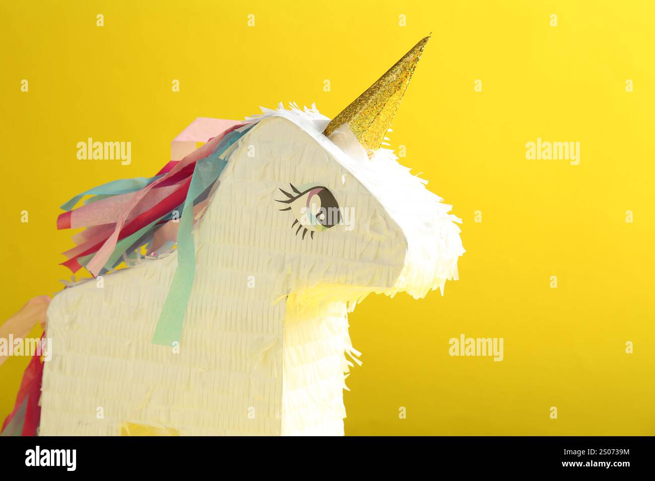 Bright pinata in shape of unicorn on yellow background Stock Photo - Alamy