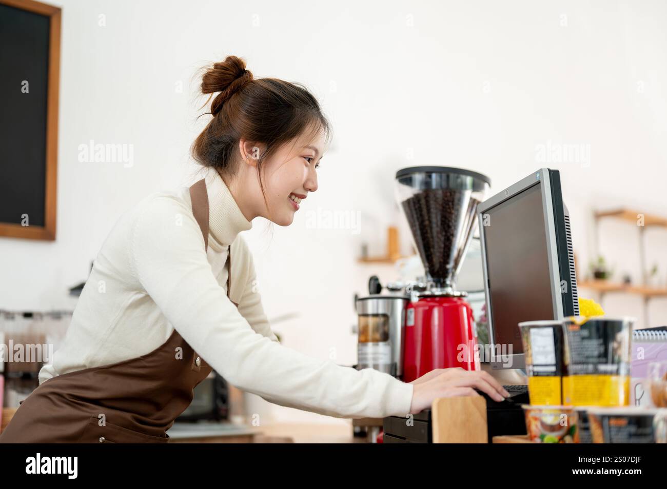 A friendly, smiling young Asian female coffee shop staff member or ...